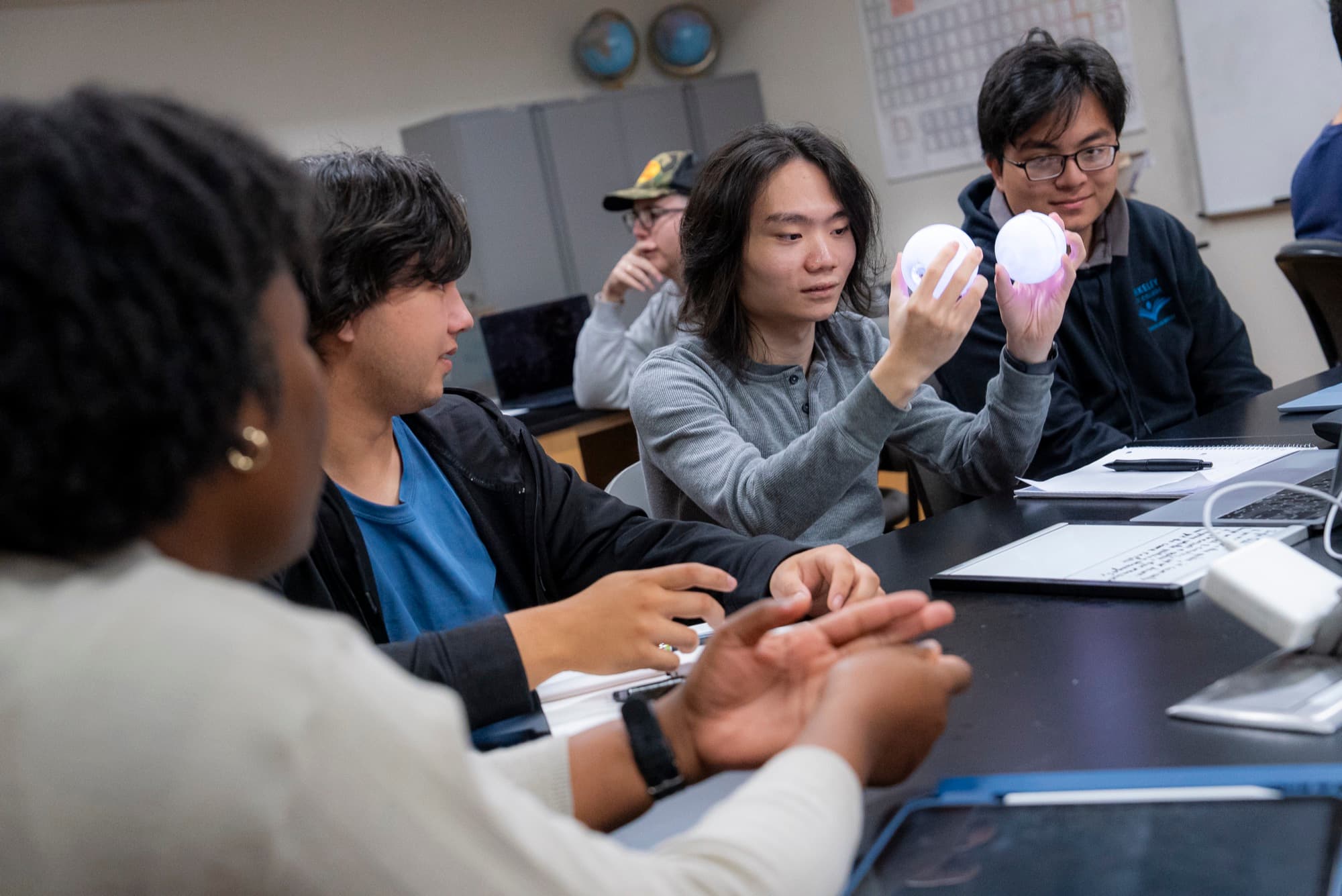 A student holding up two Qubis while classmates look on