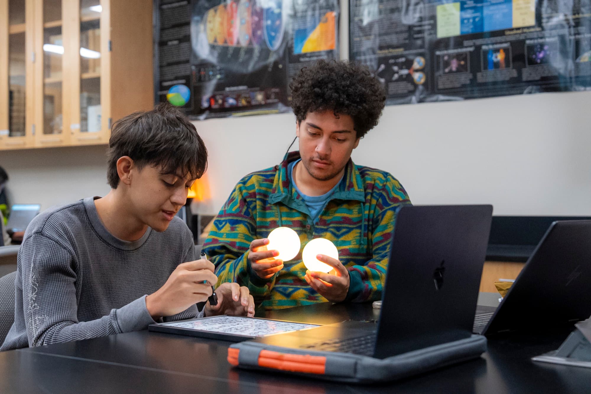 Two BERQ students measuring a pair of glowing Qubis at a lab bench