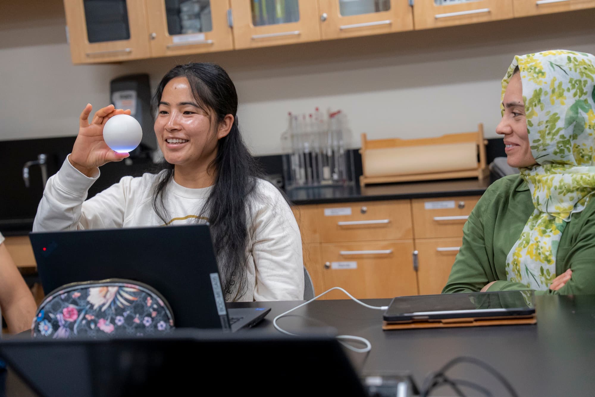 A BERQ student smiling and holding up a Qubi