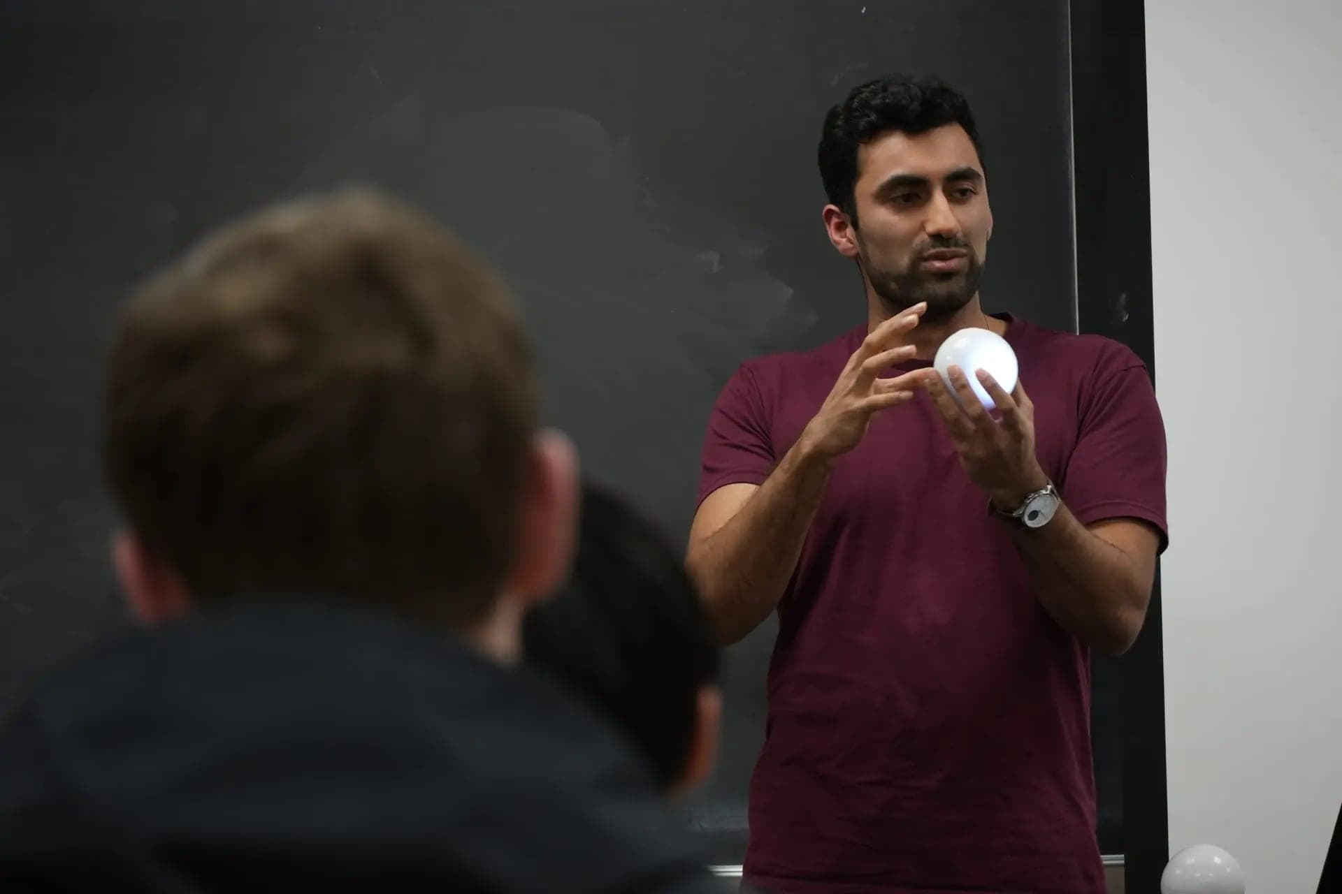Sohum Thakkar holding a glowing Qubi in front of a University of Maryland class