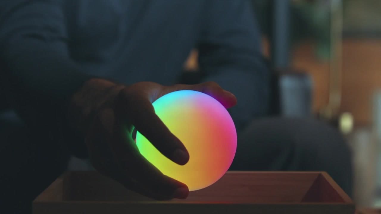 A hand holding a glowing Qubi model qubit