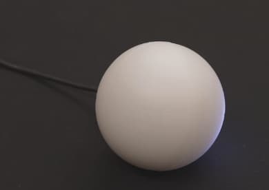 A Qubi on a dark table with a USB-C cable plugged into its back
